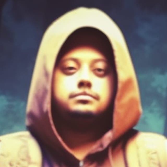 Close crop of Briz the Sage’s artist portrait: wearing a hood, looking calmly ahead.