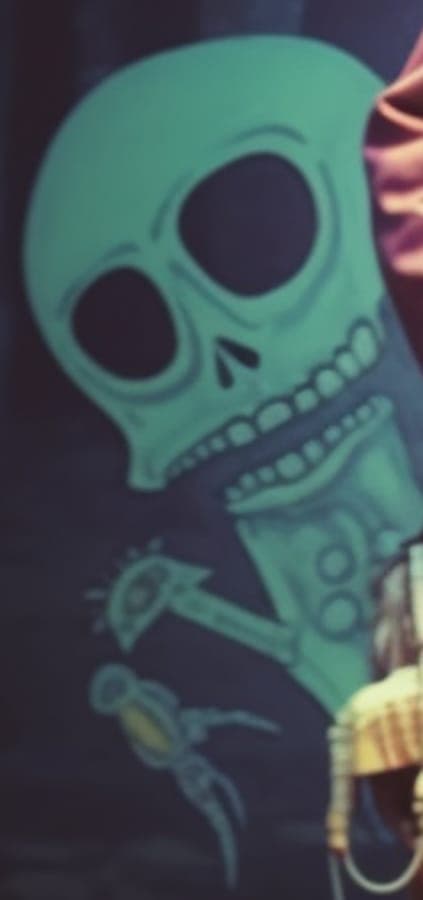 Detail from Briz’s artist portrait: Baboo Baboo, a turquoise cartoon skeleton, grinning in a dark forest.